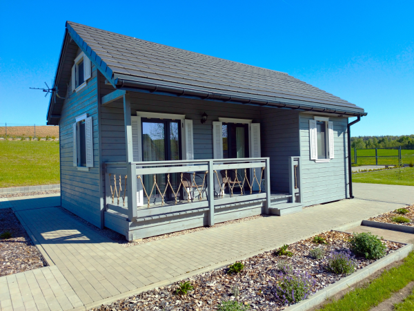 Szary Domek w Piaskach – szara elewacja z drewna i zadaszony taras